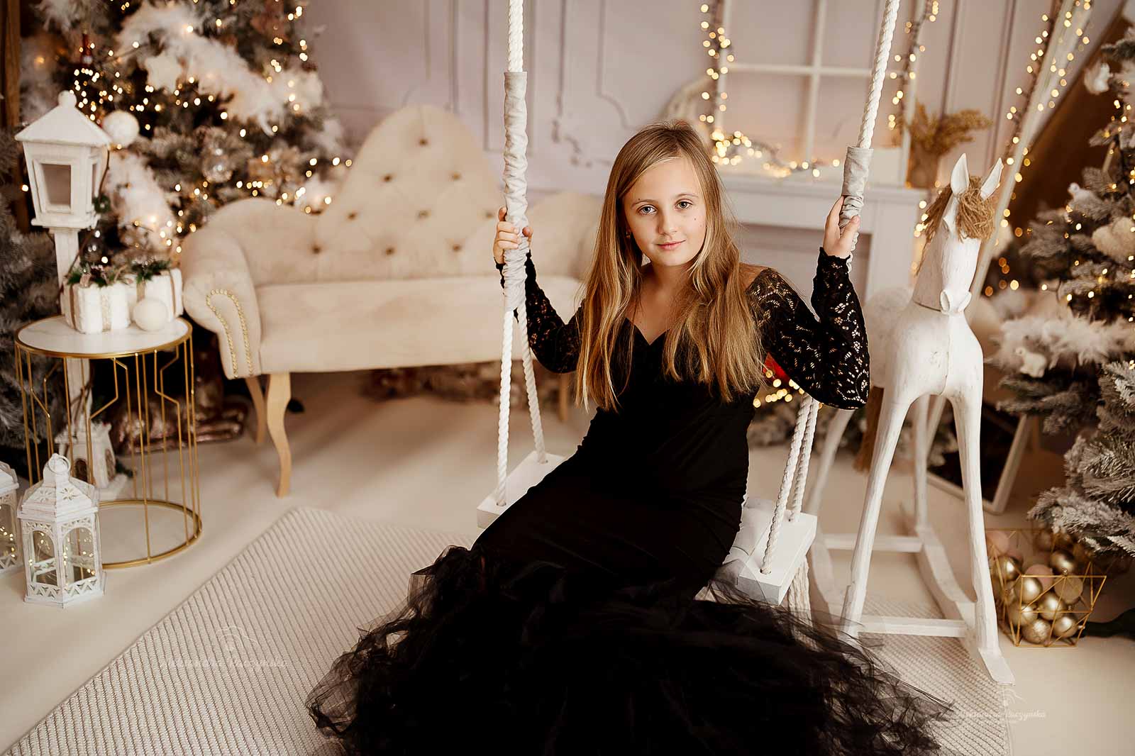 Dziecko na huśtawce w studio Drugi Brzeg w Warszawie – świąteczna sesja fotograficzna w klimacie Bożego Narodzenia.