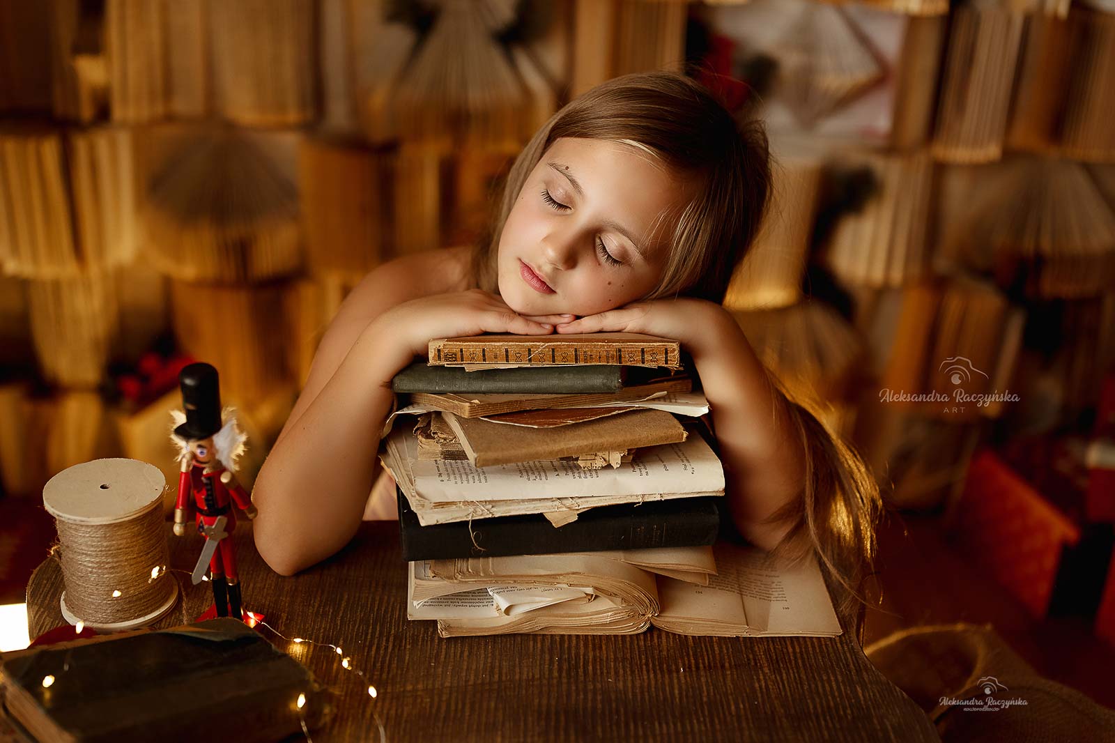 Dziecko z głową na książkach w studio Drugi Brzeg w Warszawie – świąteczna sesja fotograficzna w klimacie Bożego Narodzenia.