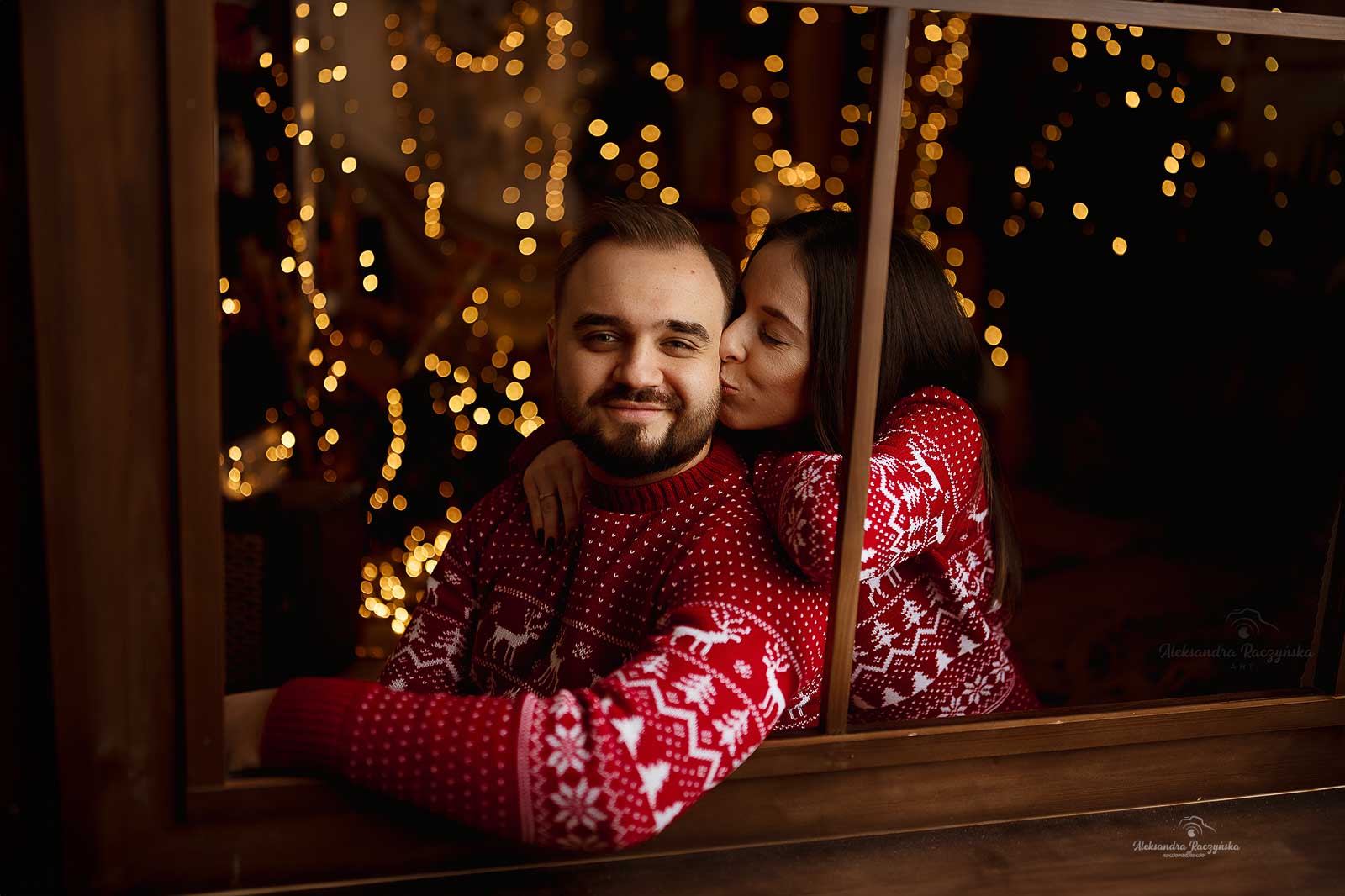 Para przy dekoracji świątecznej w świątecznych swetrach w studio Drugi Brzeg w Warszawie – świąteczna sesja fotograficzna w klimacie Bożego Narodzenia.