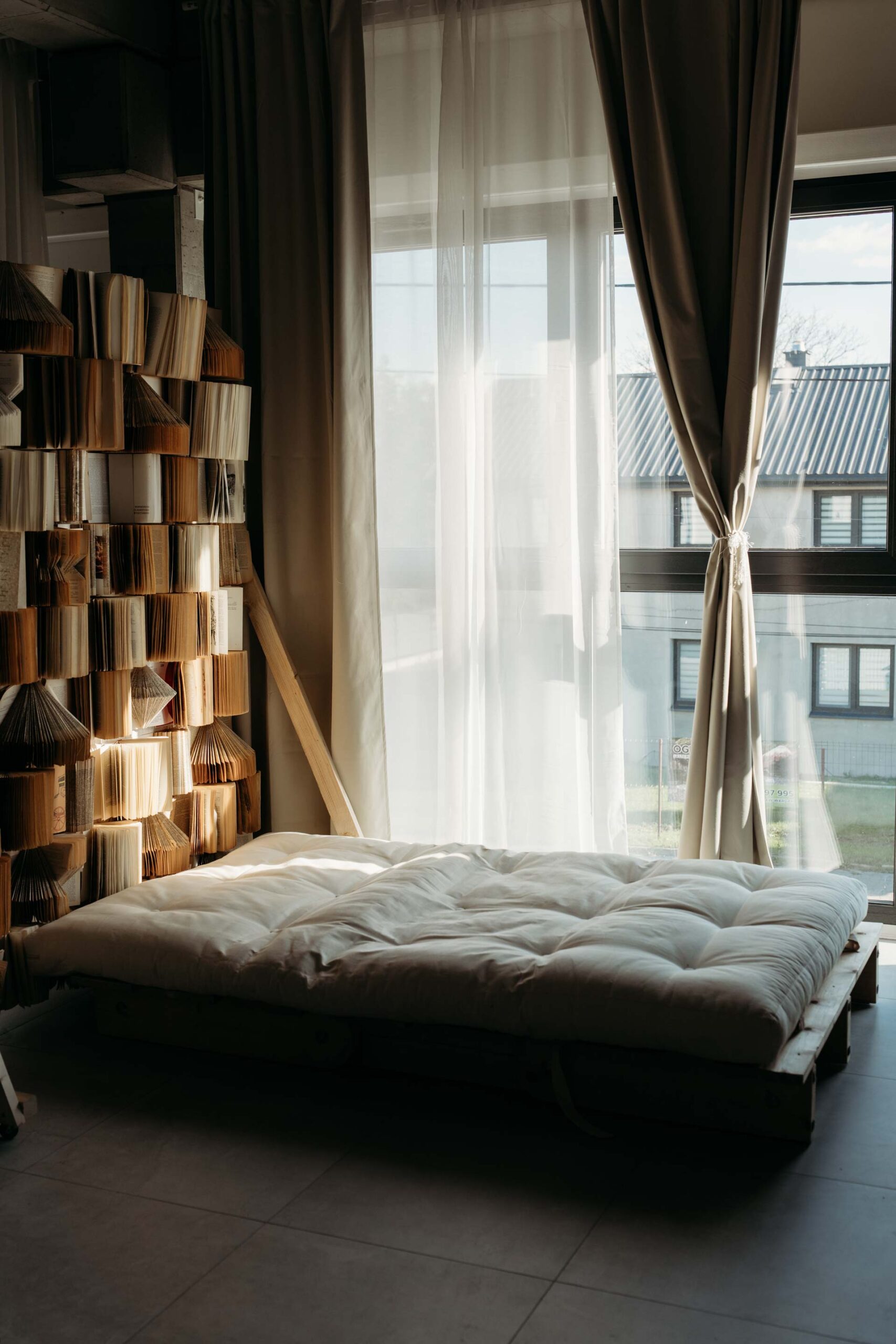 Studio fotograficzne wynajem – scenka z materacem na podłodze, światło dzienne, ściana z książkami, Warszawa